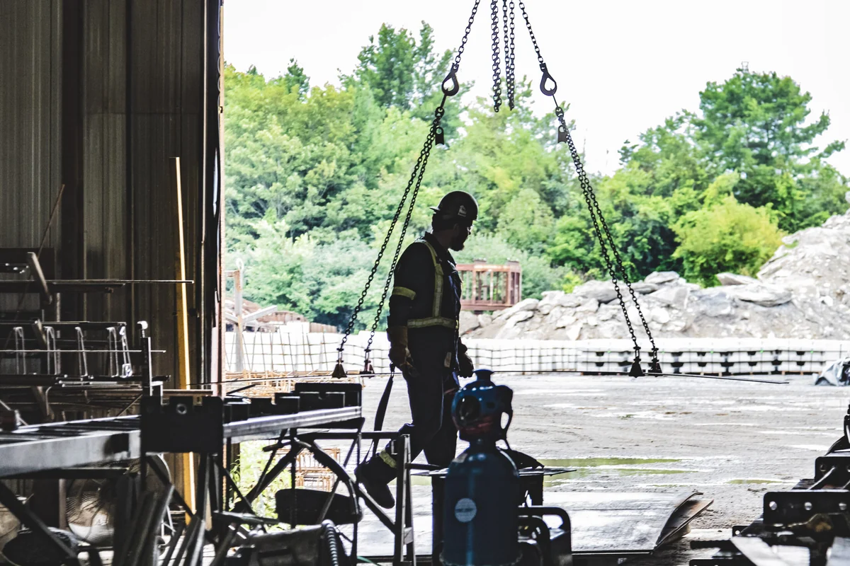 Manufacturing worker beside a lifting rig at the plant doorway