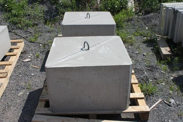 Square concrete dock weights with lifting loops stored on pallets