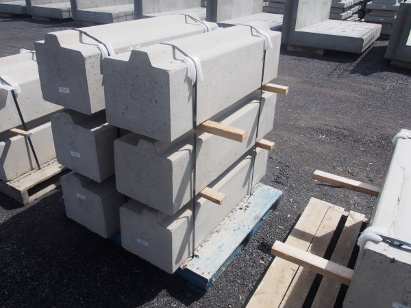 Profiled precast platform curb base components stacked on a pallet