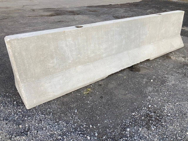 Precast concrete traffic barrier resting on gravel